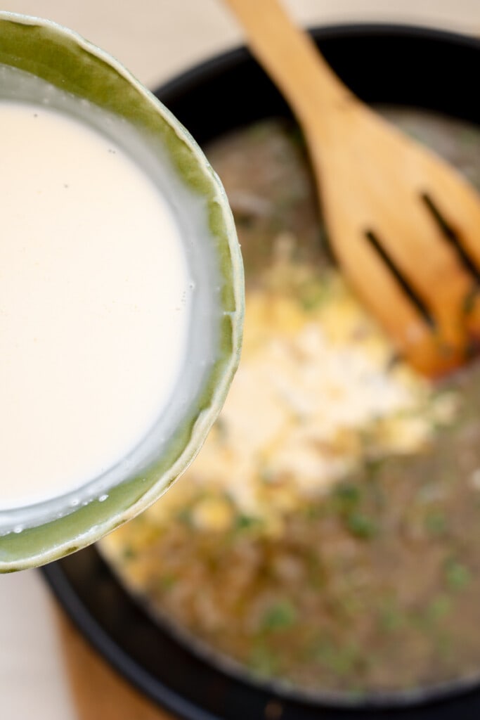 pouring cream into a pan with shallots, wine, and tarragon