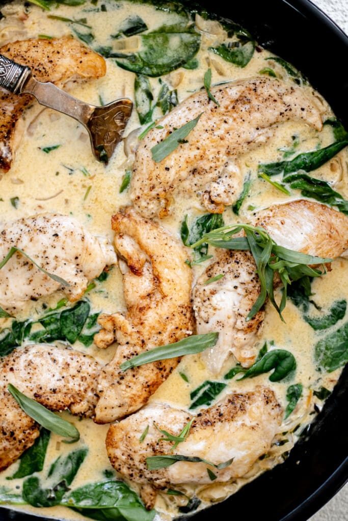 cast iron skillet with creamy tarragon chicken and a fork