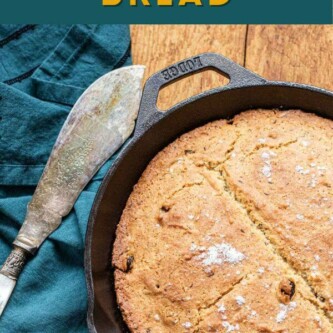 Irish soda bread in a cast iron pan next to a serving spatula and a teal tea towel.