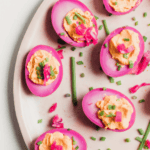 pink picked eggs cut in half on a plate with chives