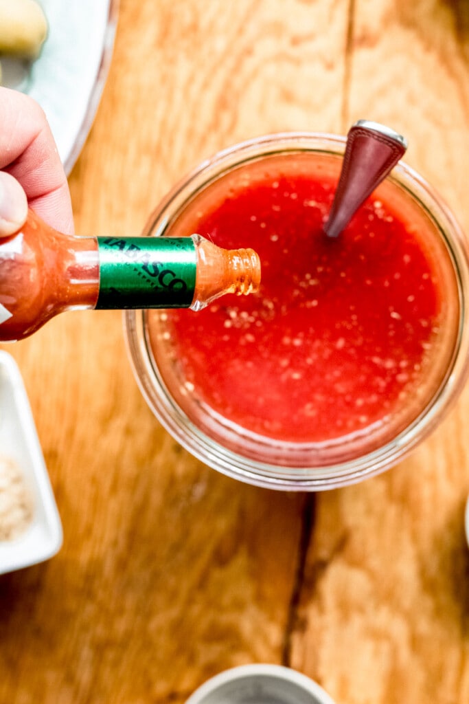pouring tabasco sauce into a bloody mary