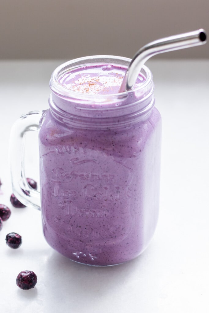 blueberry cottage cheese smoothie in a mason jar with a metal straw.