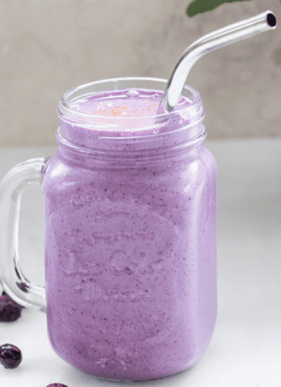 blueberry cottage cheese smoothie in a mason jar with a metal straw.
