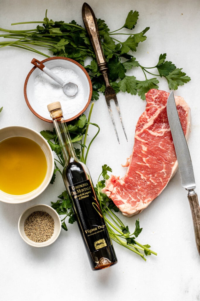 Ingredients to make tuscan steak on a white background