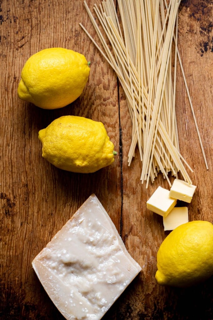 lemon, pasta, butter, and cheese on a wood surface