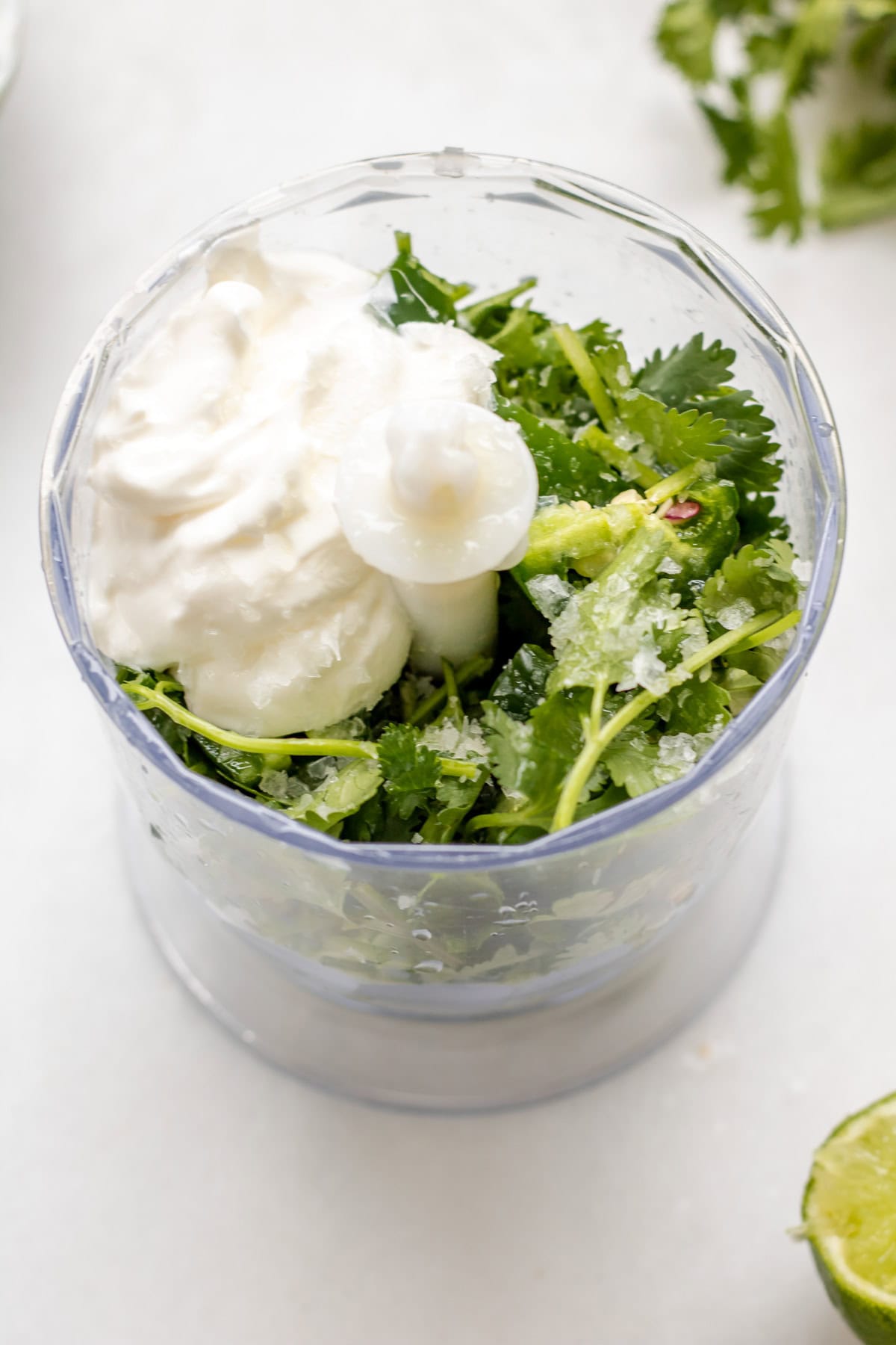 a mini food processor with ingredients for cilantro jalapeno sauce