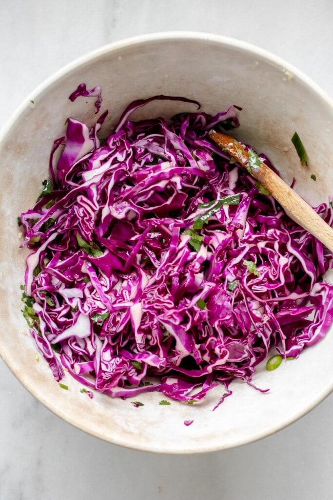 Ingredients for cabbage sauerkraut probiotic slaw in a large bowl.