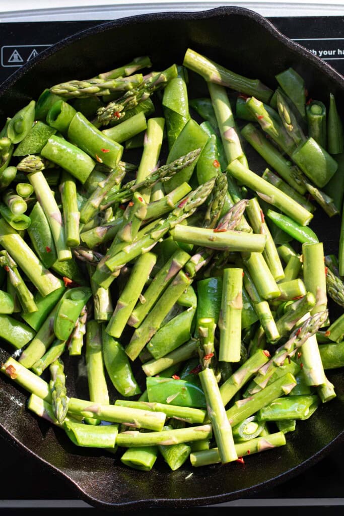 sugar snap peas and asparagus in a cast iron skillet