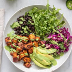 Bowl containing roasted sweet potato and black bean salad with avocado slices.
