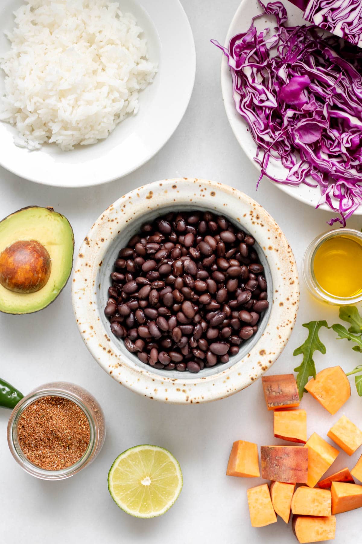 1 bowl of rice, 1 bowl of red cabbage, 1 bowl of black beans. 1 split avocado, chopped sweet potato pieces, a lime and a jar of spice mix.
