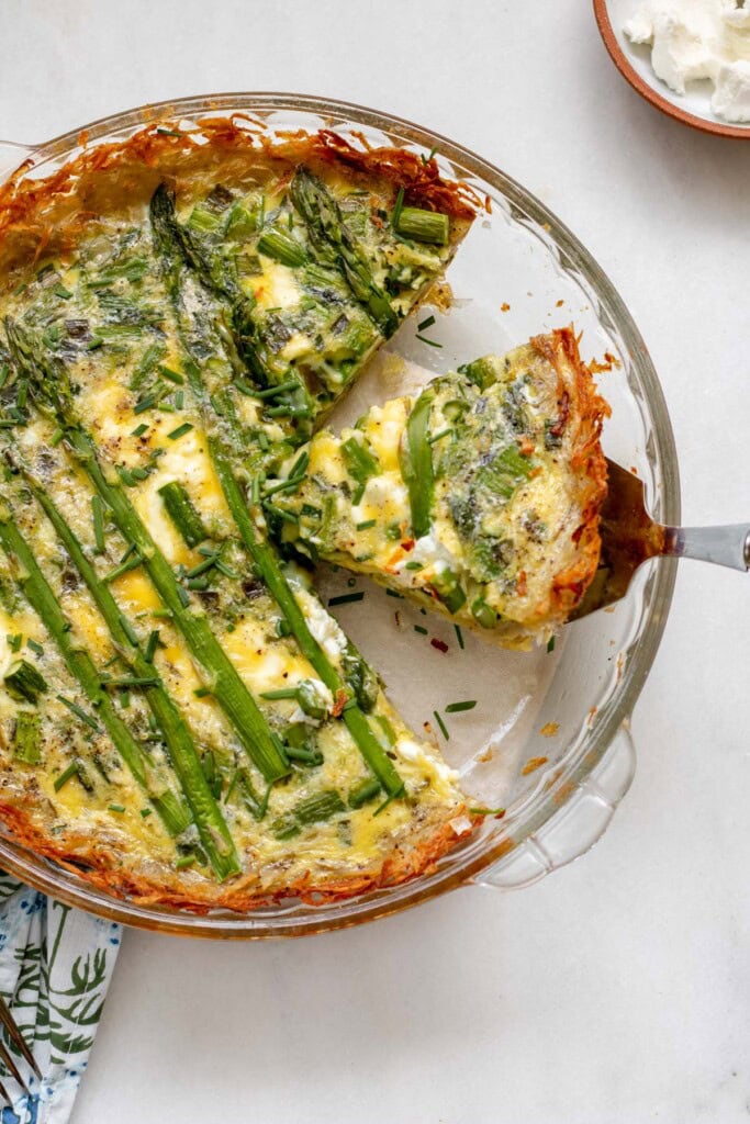 serving utensil holding a slice of asparagus quiche with potato crust