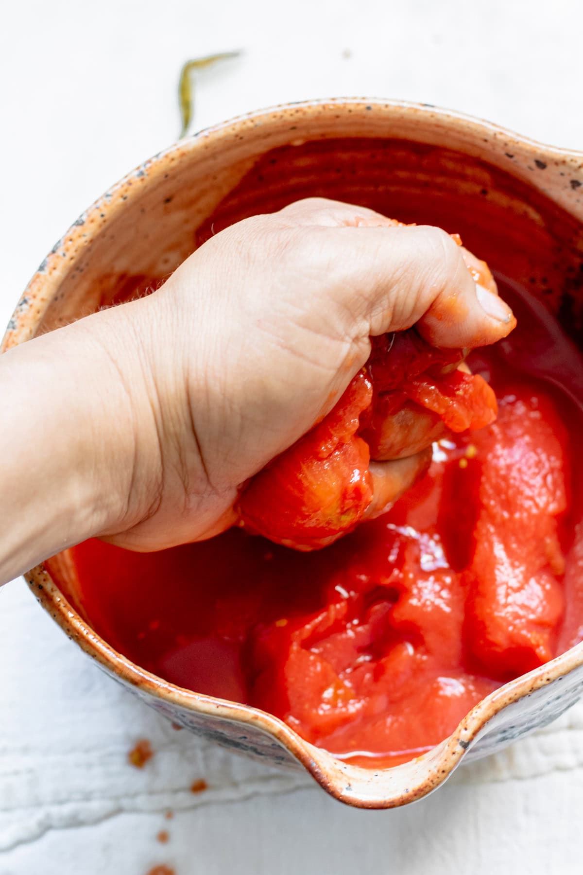 squeezing whole tomatoes with hand