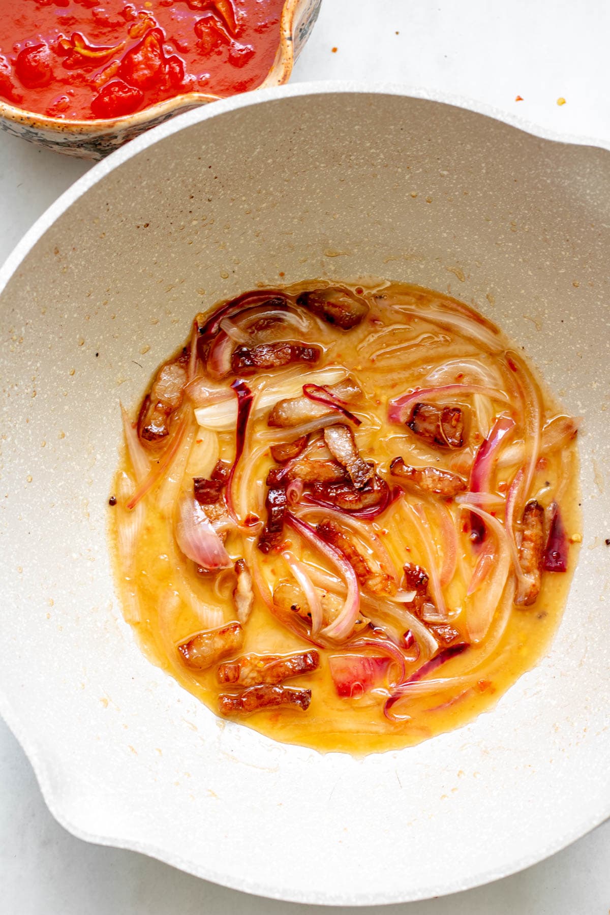 pan of deeply sauteed onions and guanciale in olive oil