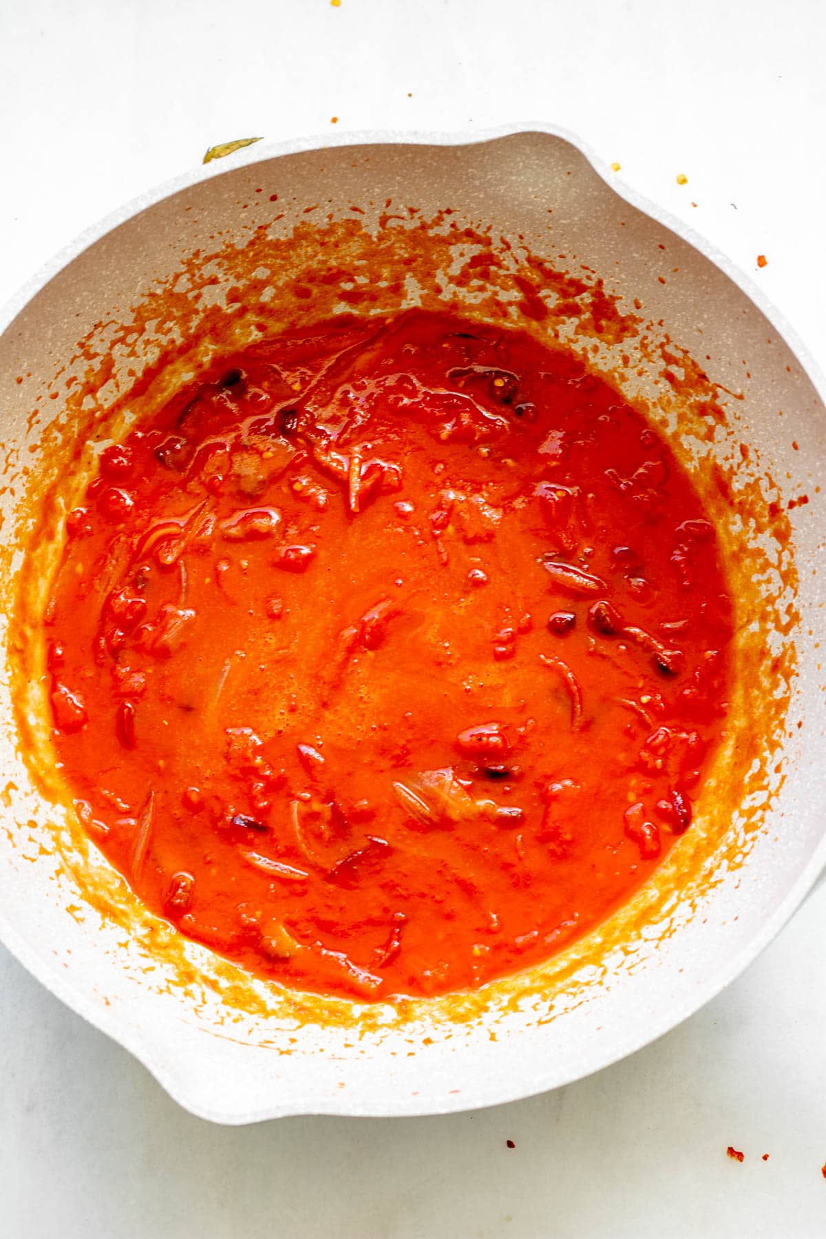 pan of simmering tomato sauce with onions and guanciale