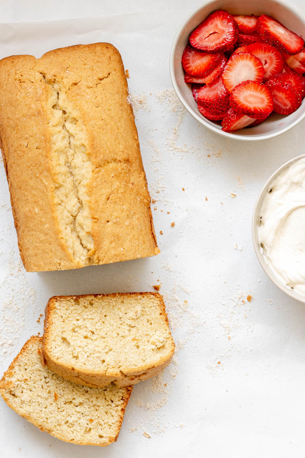 gluten free pound cake loaf with a side of whipped cream and strawberries