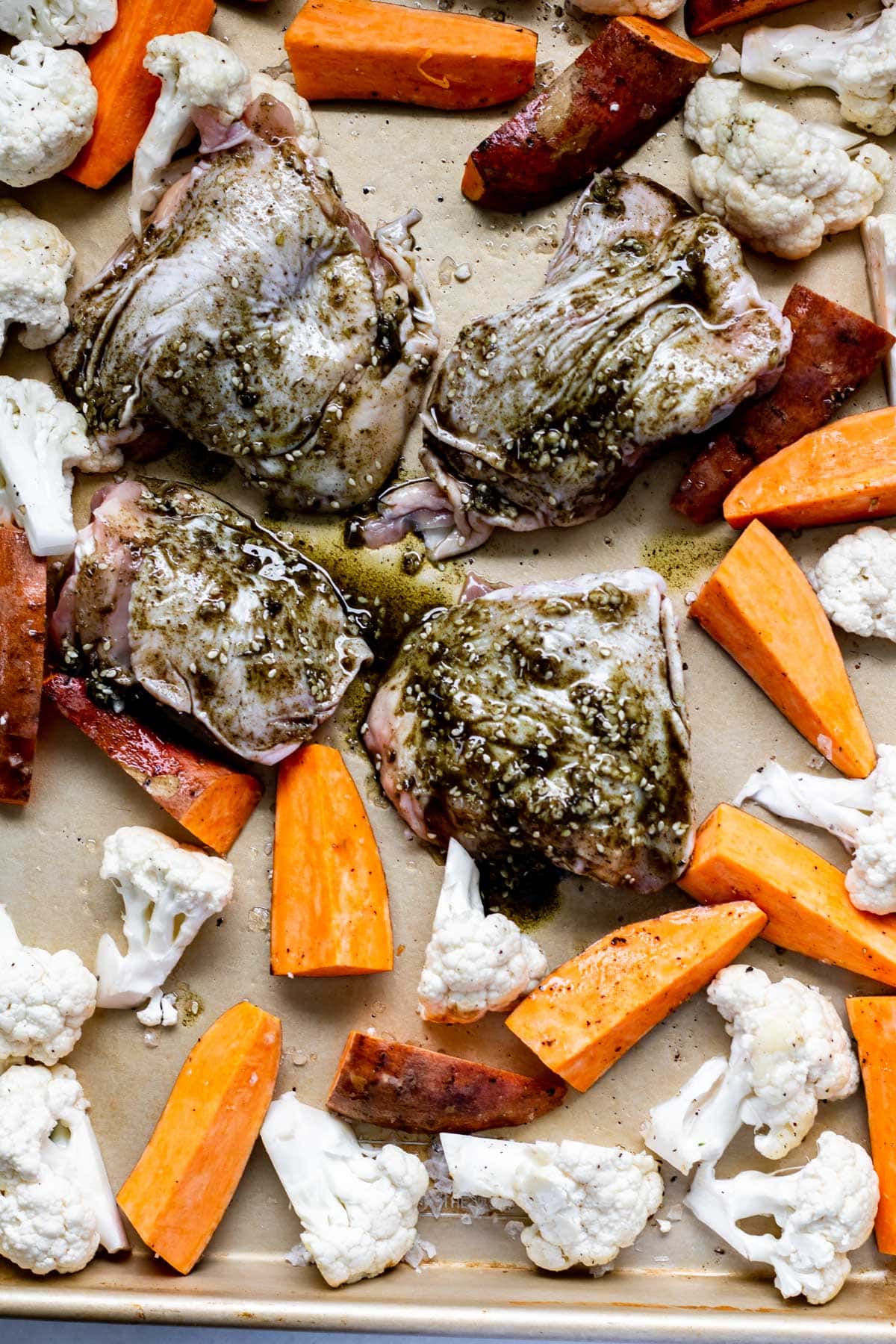 chicken and sweet potatoes and cauliflower on a sheet pan before roasting