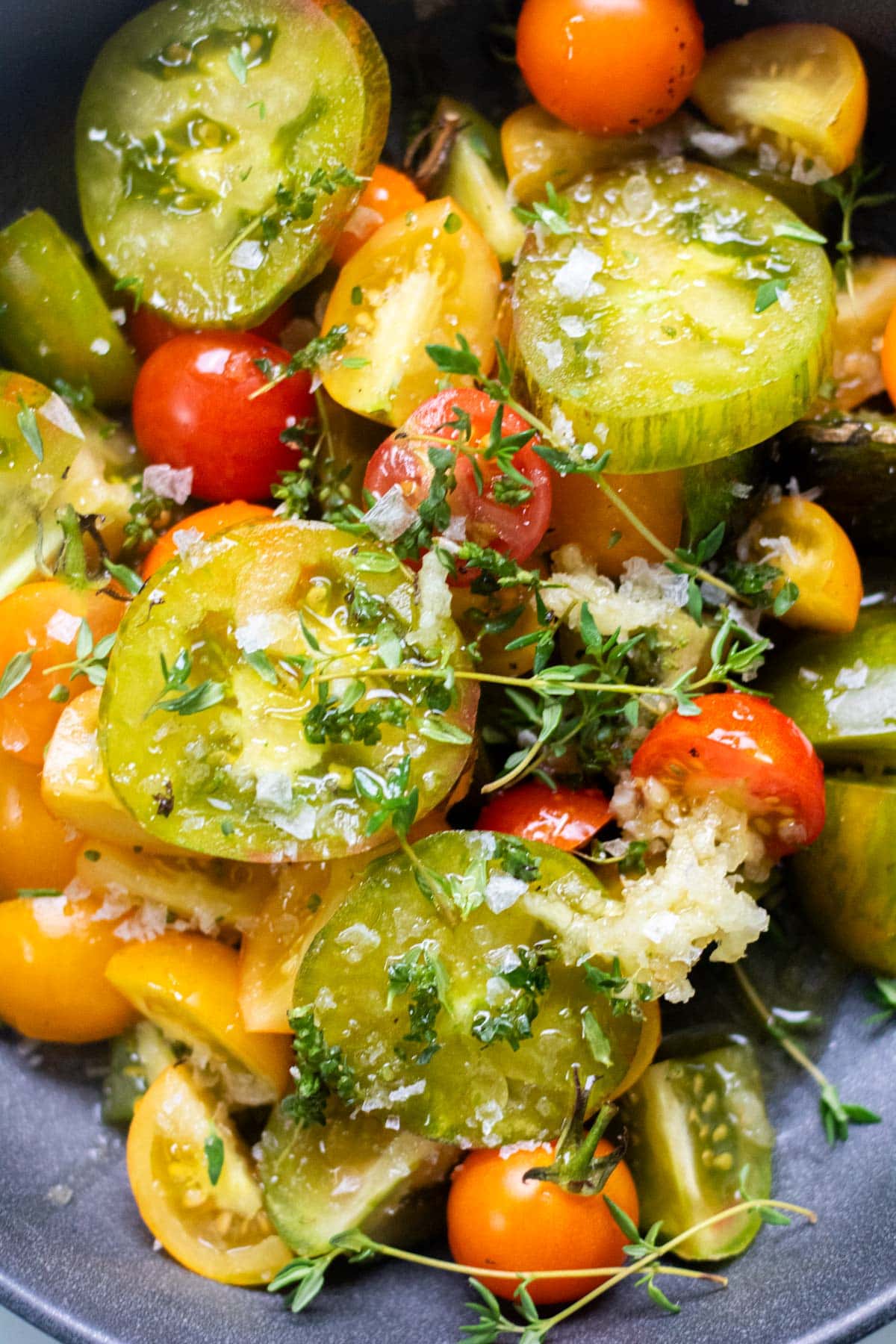 sliced tomatoes in a bowl with garlic and herbs