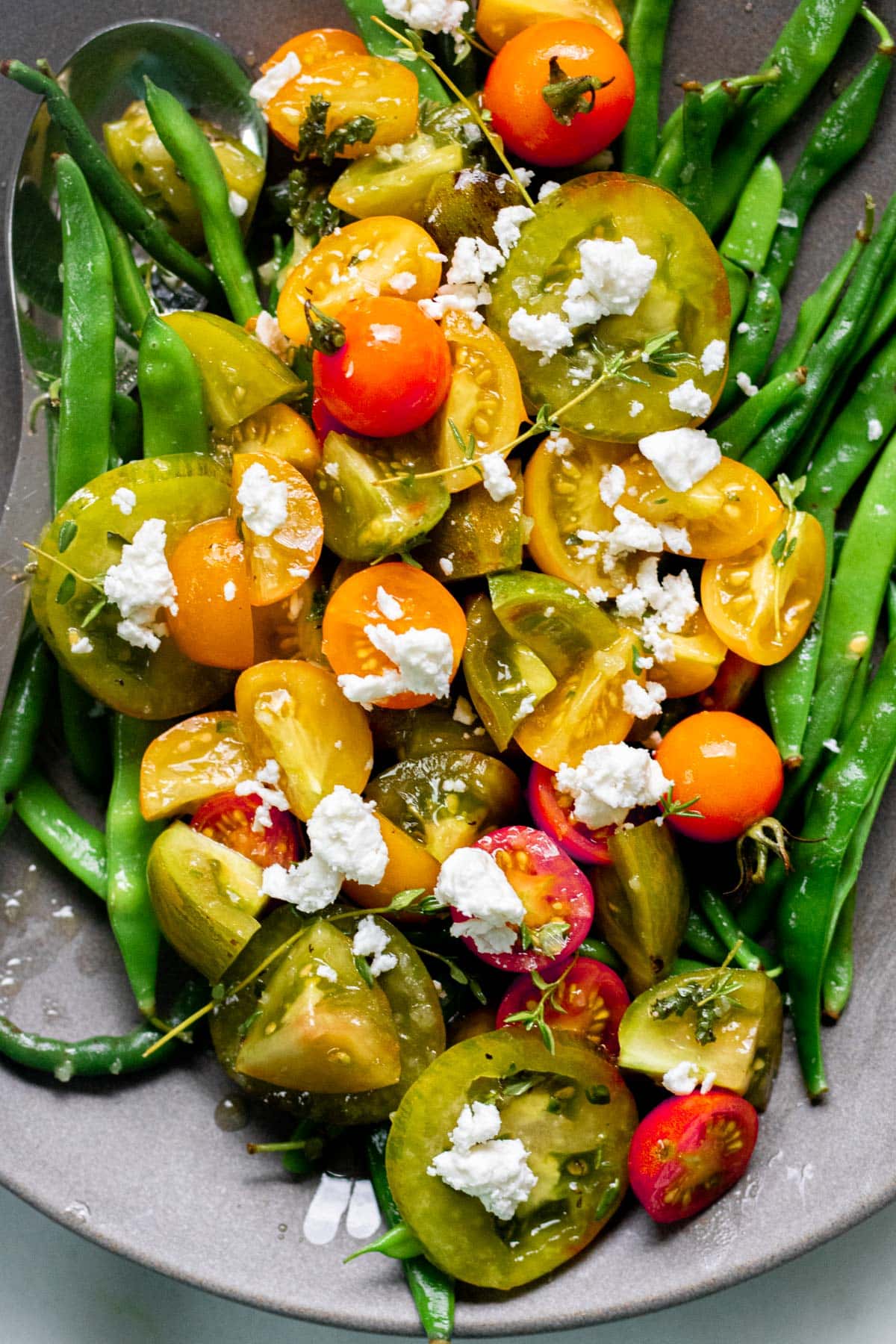 plate of mediterranean green bean salad with tomatoes, herbs and feta cheese