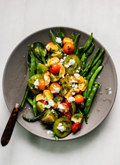 plate of mediterranean green bean salad with tomatoes, herbs and feta cheese