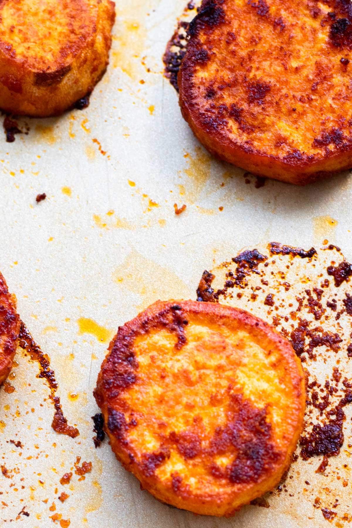 sliced and spiced sweet potato rounds on a sheet tray