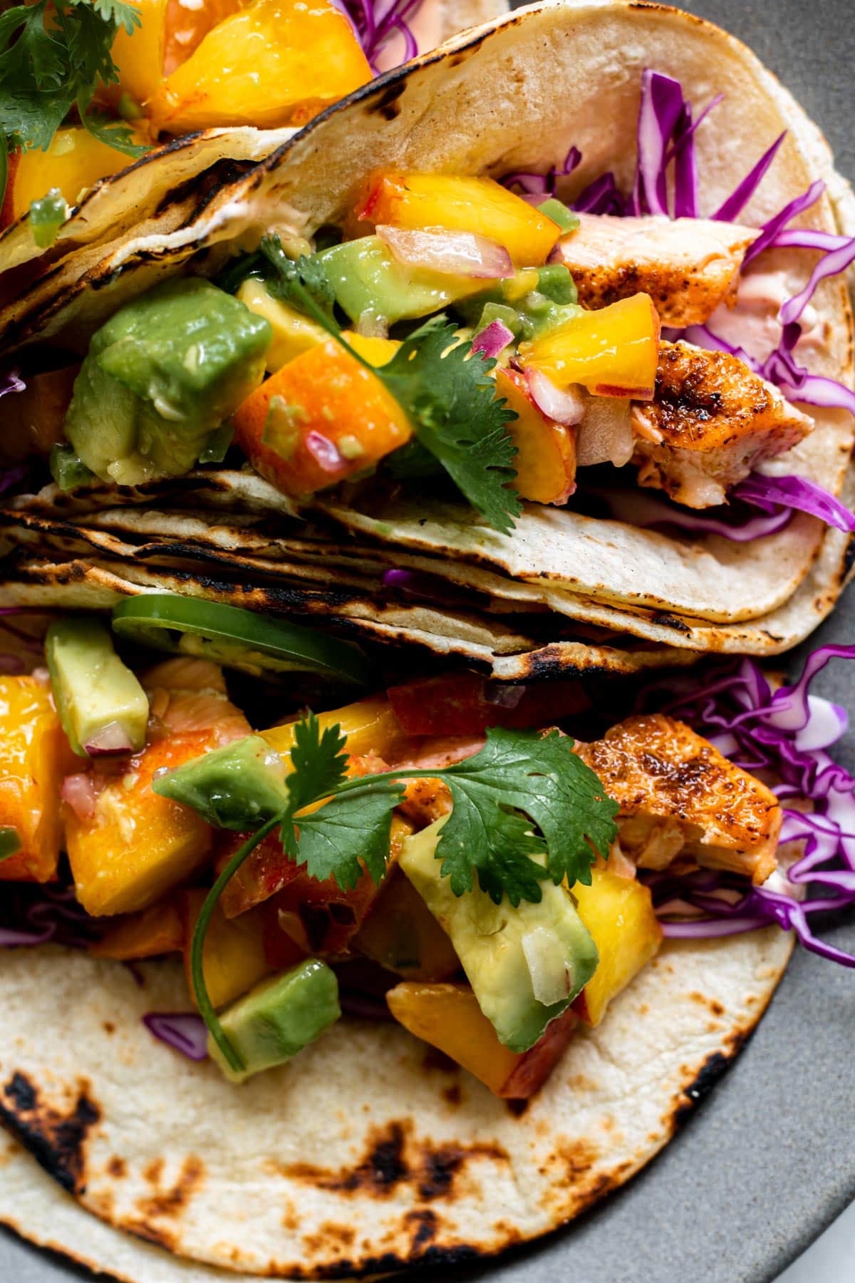 close up shot of peach salsa on top of blackened salmon in a taco