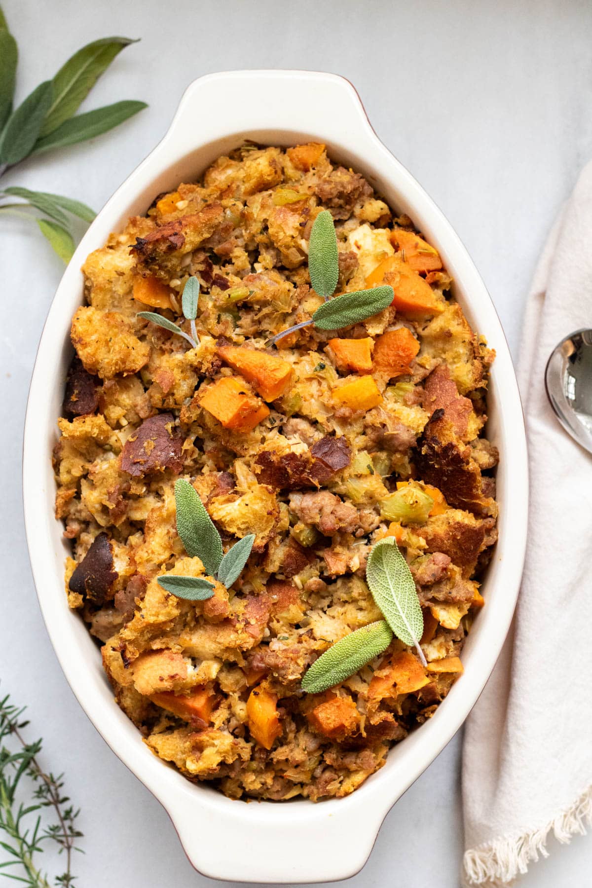 large casserole dish of butternut squash stuffing with fresh sage leaves on top