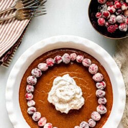 crustless pumpkin pie with forks in the background and sugared cranberries in a bowl