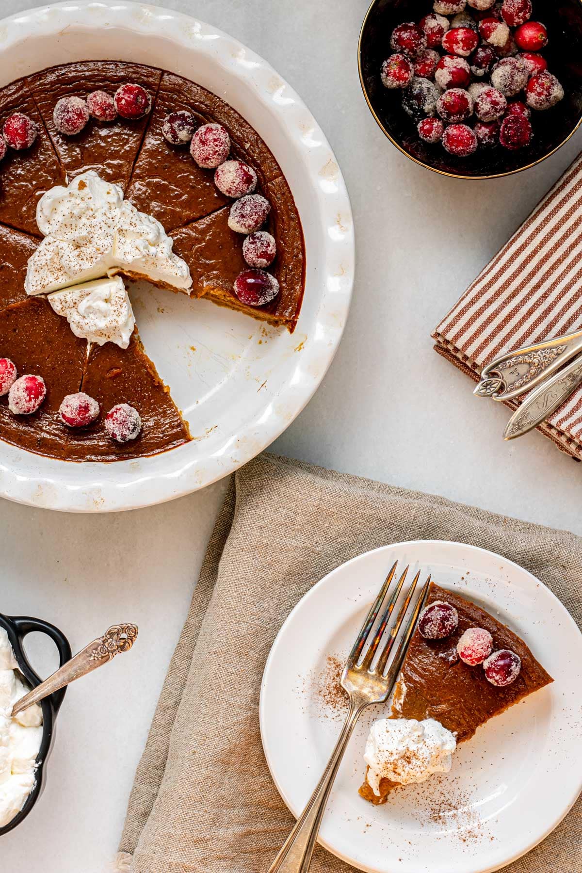 pumpkin pie in a pie dish with a slice cut out and a plate with a slice of crustless pumpkin pie