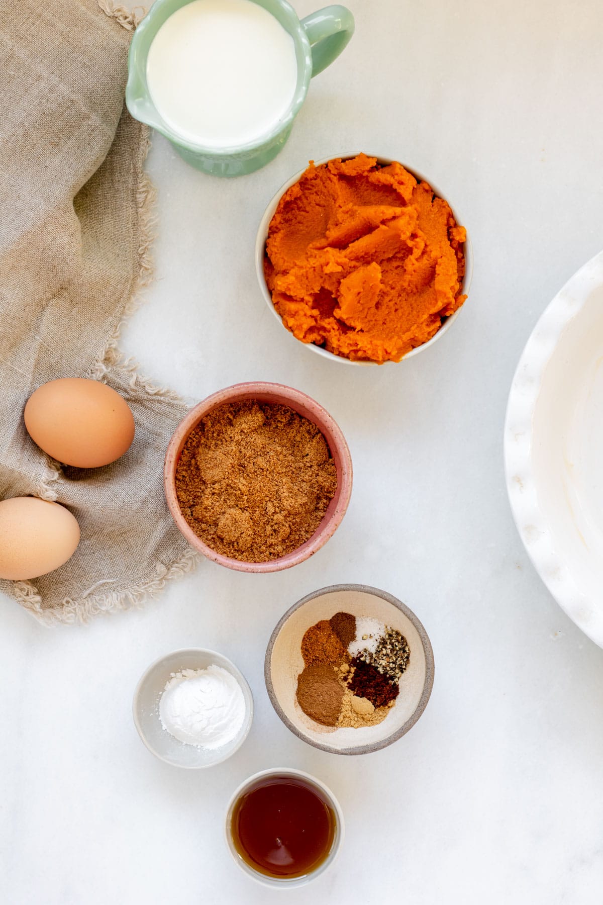 Ingredients in small bowls on a white background for crustless pumpkin pie