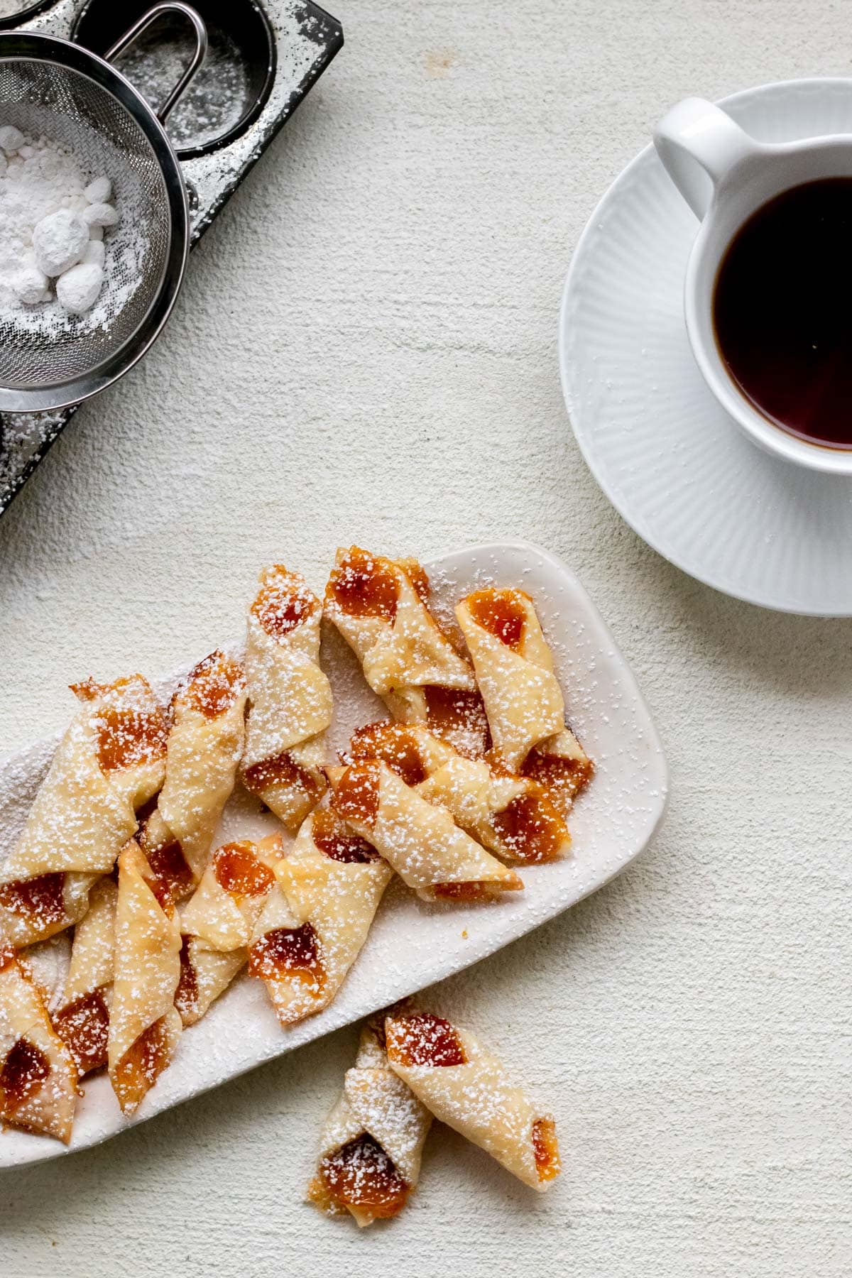A plate of Hungarian Kiffles with tea in the background