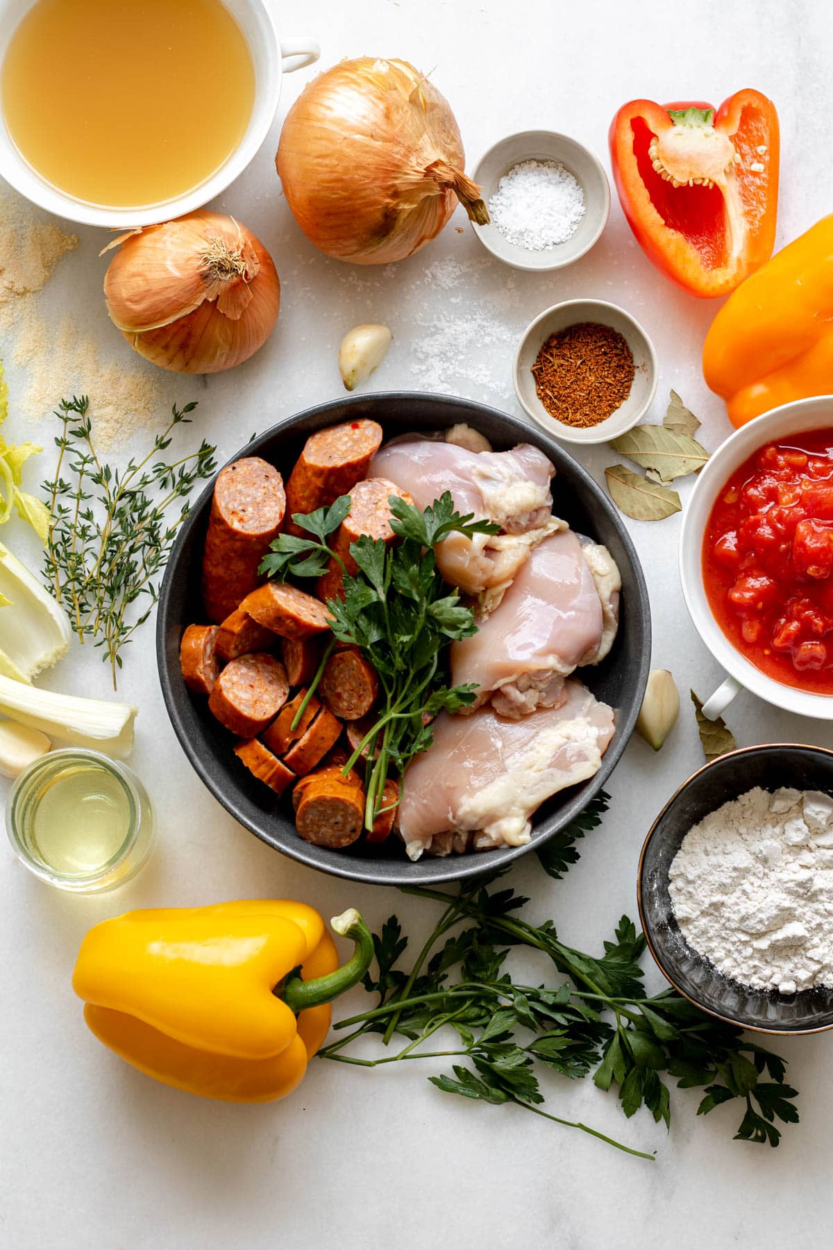 ingredients needed for gluten free chicken and sausage gumbo in little bowls on white surface