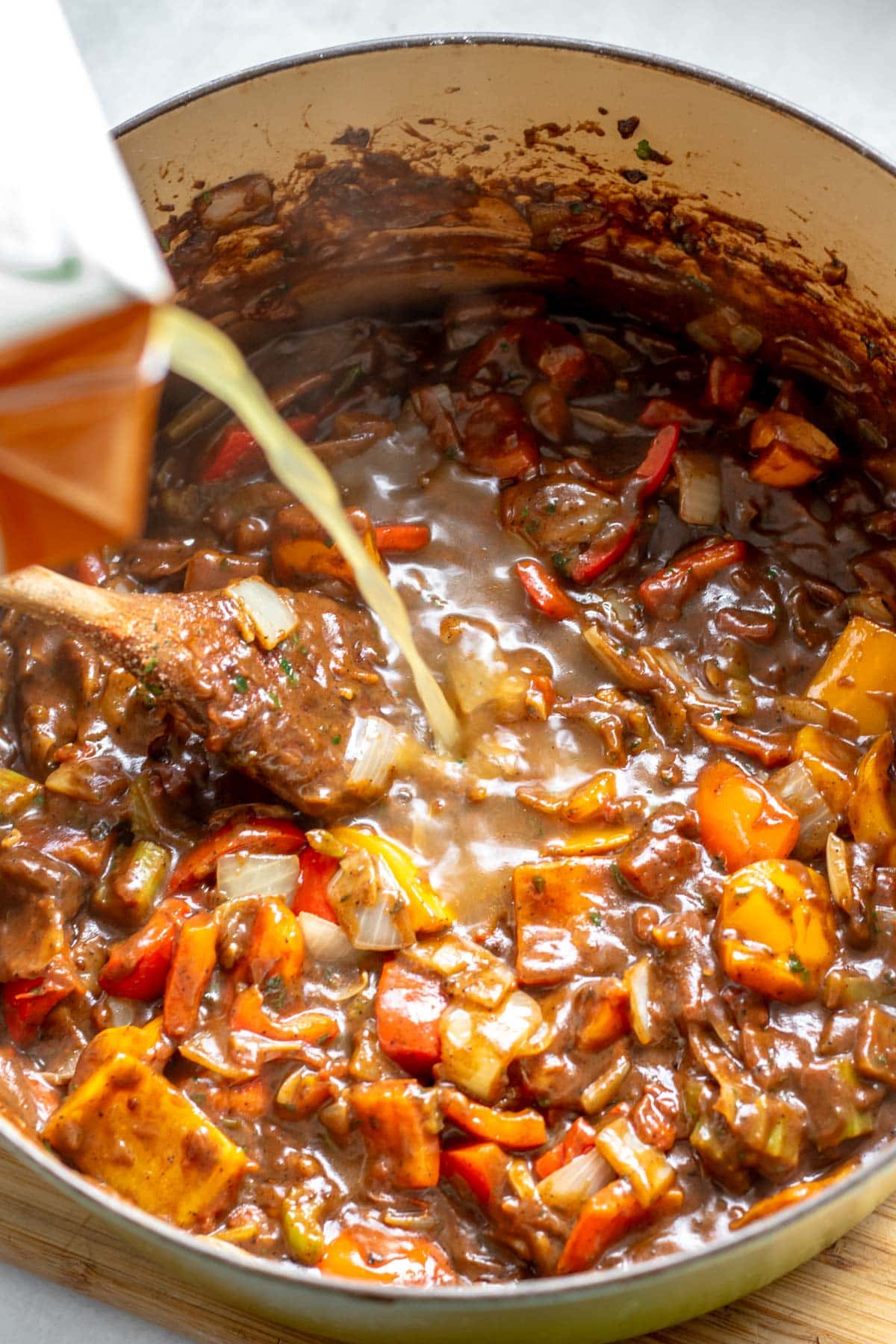 adding stock to a pot of gumbo