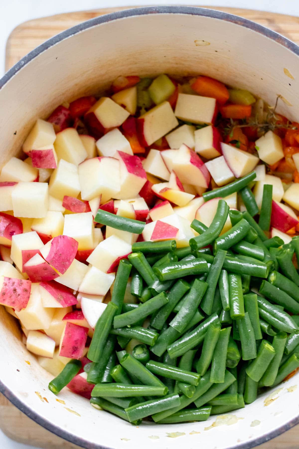 adding red potatoes and green beans to a pot of minestrone soup