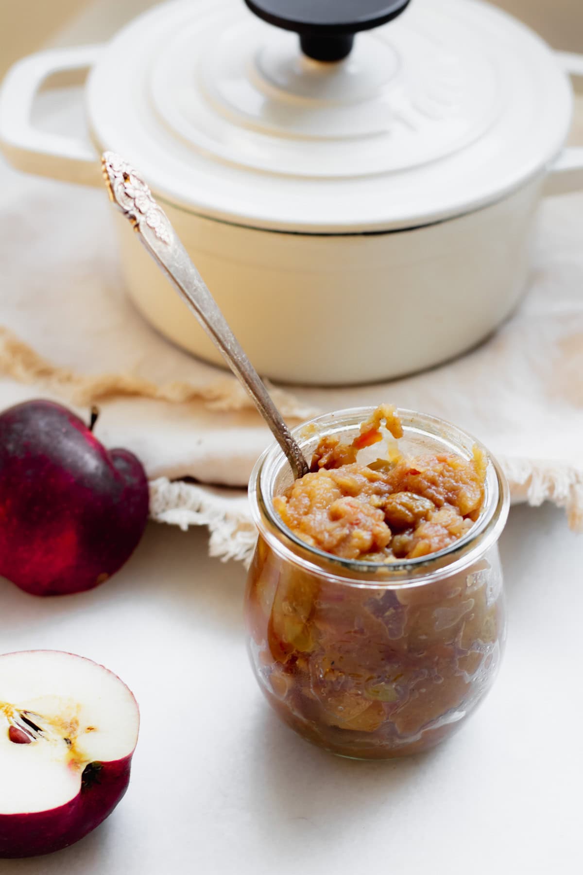 small jar of cooked apple chutney with an apple and a pot in the background