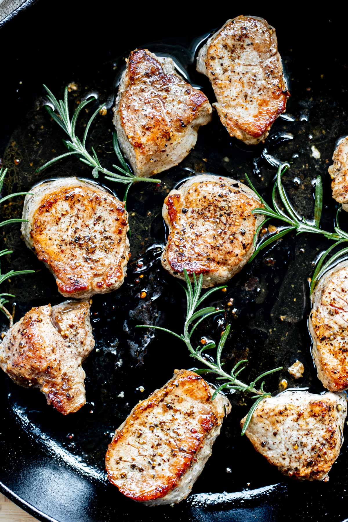 pork medallions cooking in a cast iron skillet