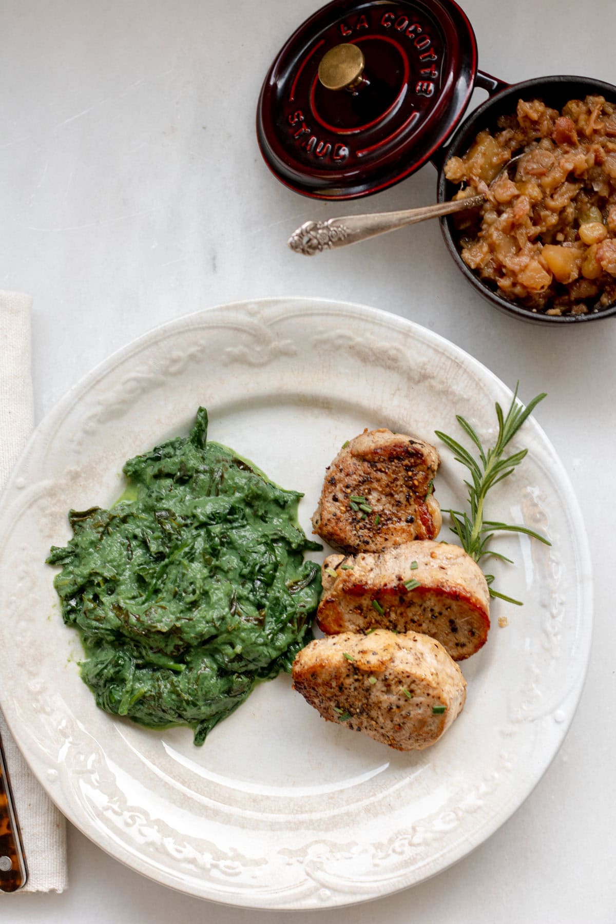 pork medallions on a plate with fresh rosemary and creamed greens