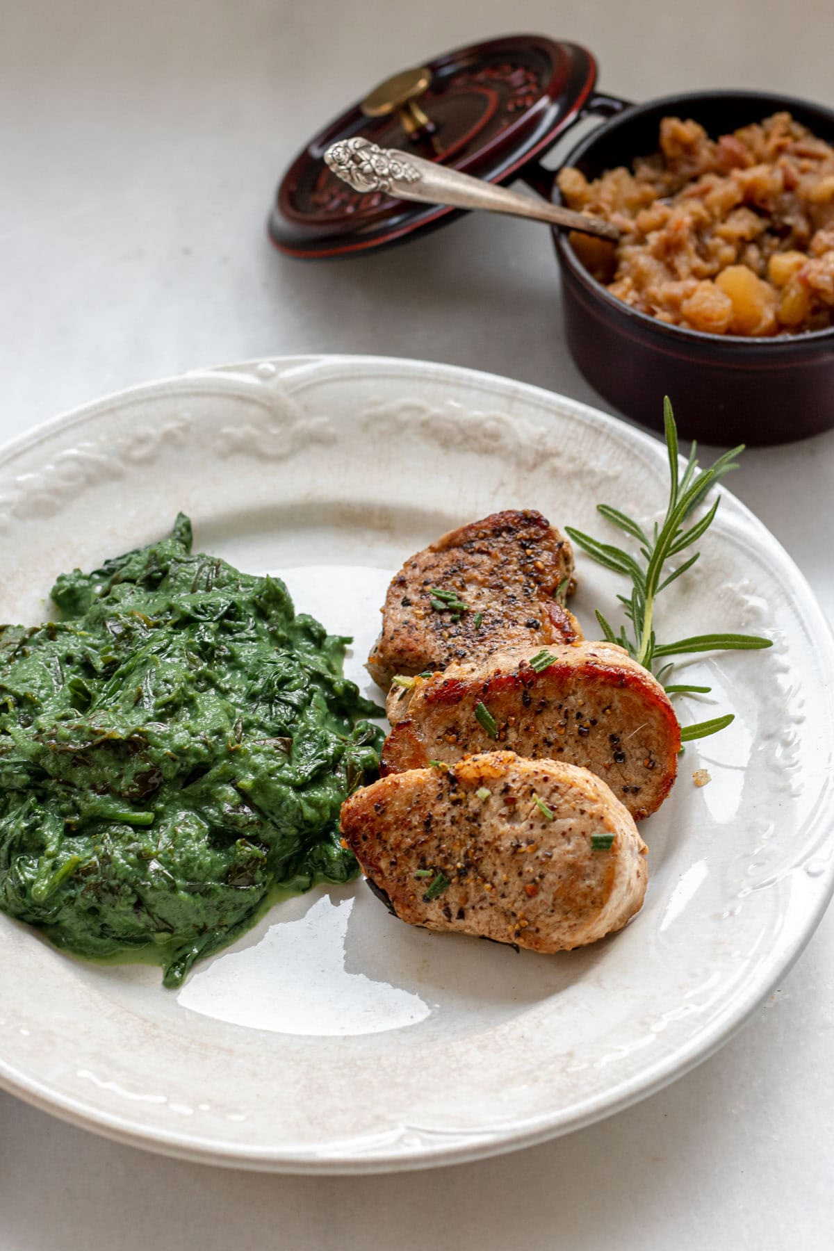 pork medallions on a plate with fresh rosemary and creamed greens
