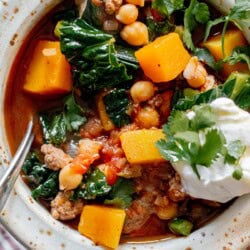 a close up shot of ground lamb stew with butternut squash, kale, and chickpeas