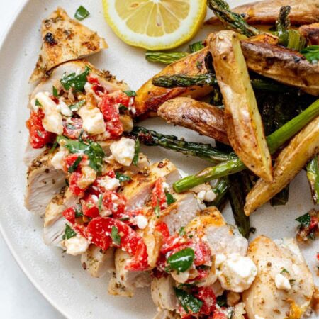 a plate of greek sheet pan chicken with roasted red pepper salsa and roasted potatoes