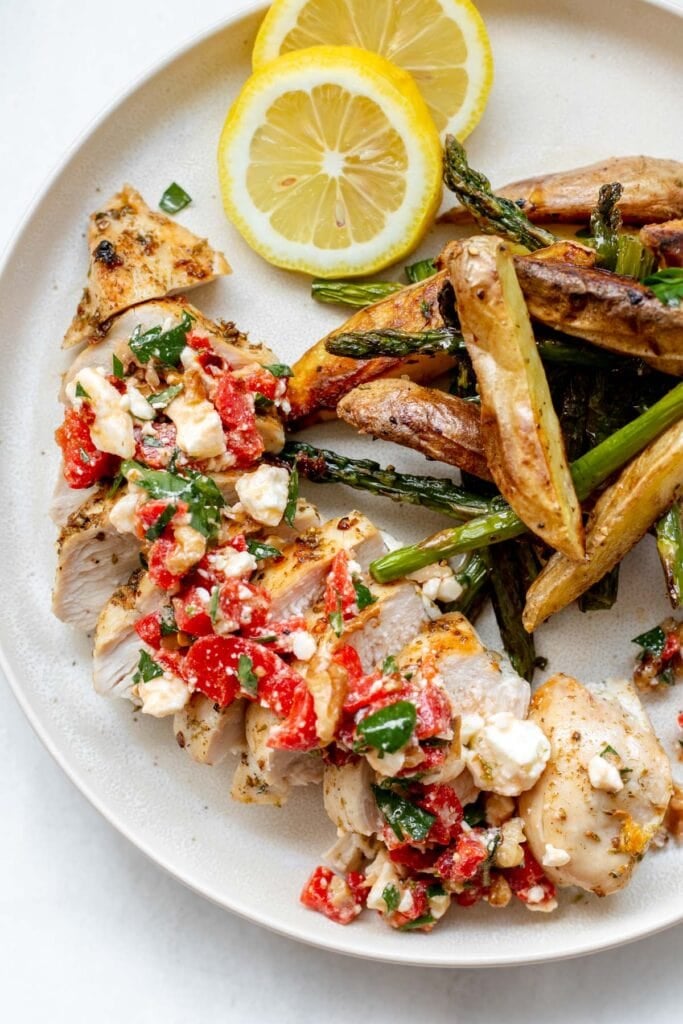 a plate of greek sheet pan chicken with roasted red pepper salsa and roasted potatoes