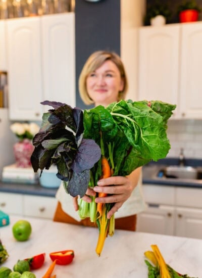 abra pappa holding a big bunch of greens in her kitchen