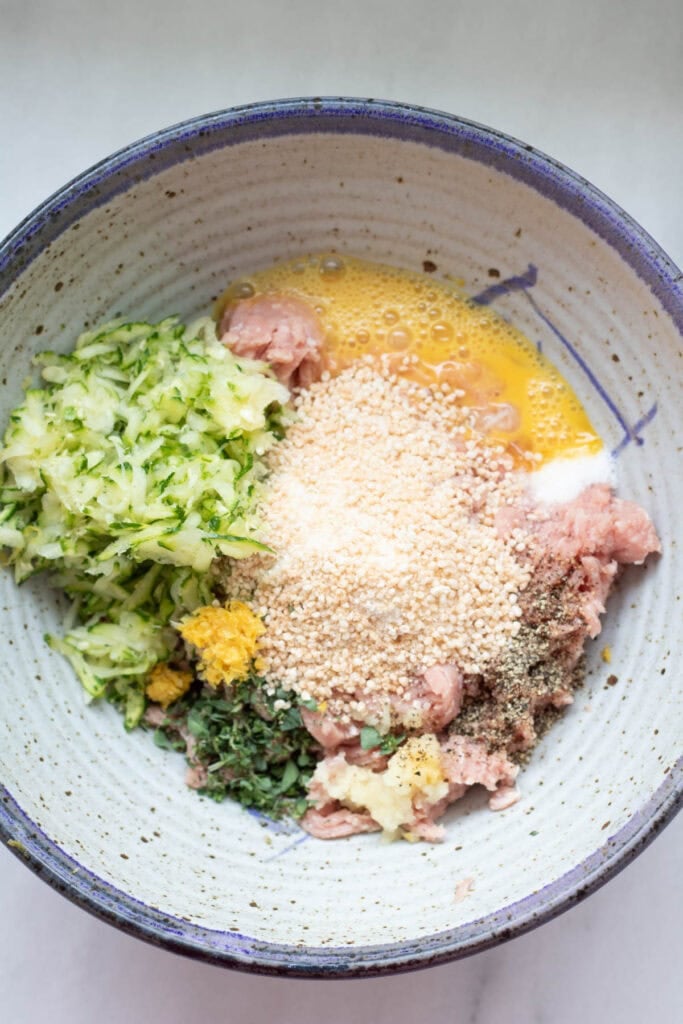 bowl of ground turkey, shredded zucchini, and other ingredients about to be made into meatballs.
