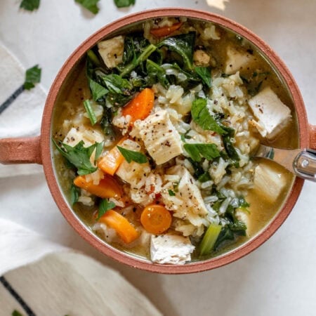a brown bowl with handles with chicken rice soup