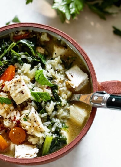 a bowl of chicken rice soup with a spoon inside