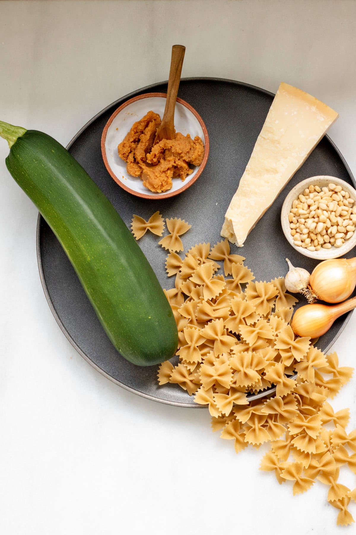 ingredients needed for creamy zucchini pasta on a grey platter