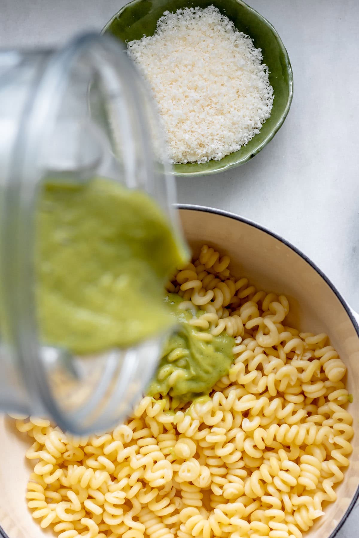 pouring green creamy zucchini sauce into pot