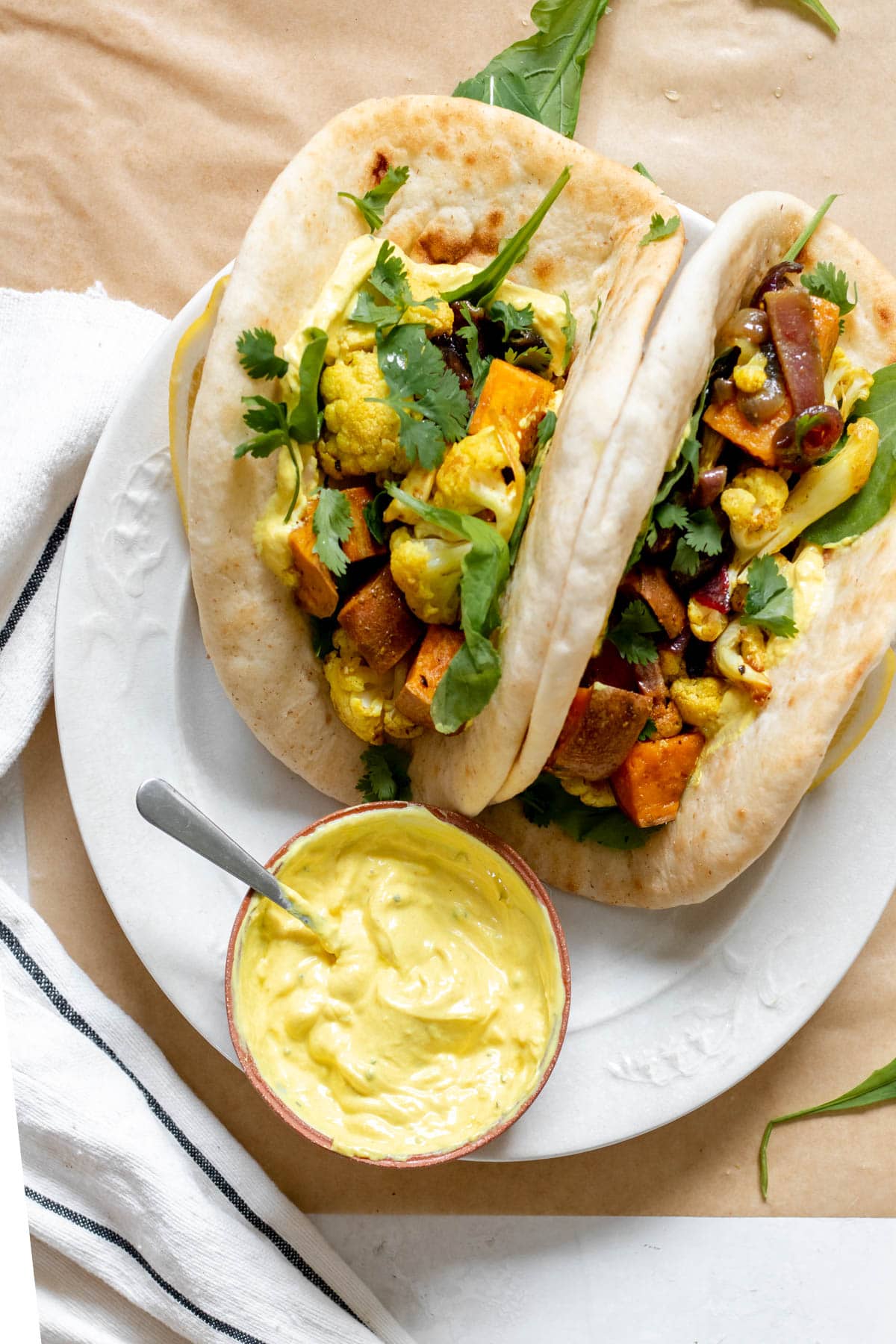 2 pita stuffed with curried roasted cauliflower and sweet potato on a plate