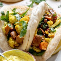 2 pita stuffed with curried roasted cauliflower and sweet potato on a plate