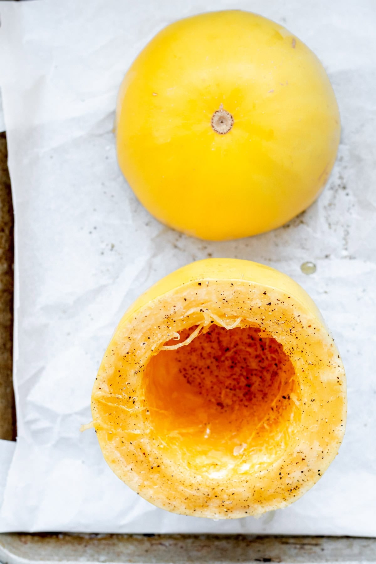 spaghetti squash cut in half, on a baking sheet
