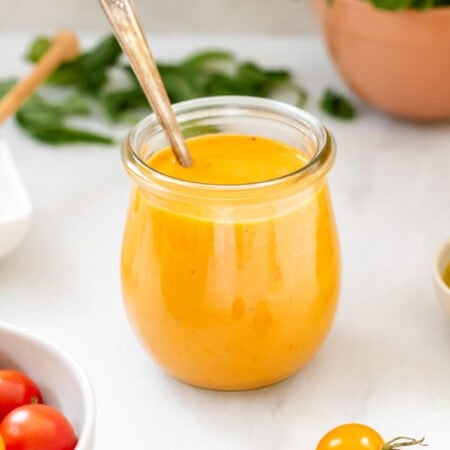 tomato vinaigrette in a small jar next to cherry tomatoes